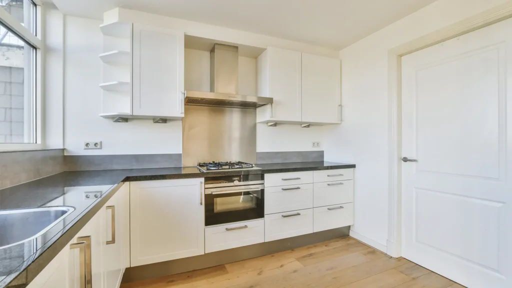 Cocina reformada con muebles blancos y encimera oscura en Burriana.